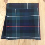Children's MacKenzie tartan kilt in blue, green, red and white plaid folded on wooden background