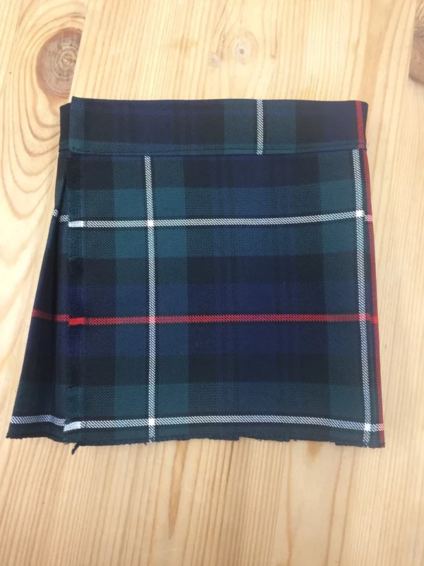 Children's MacKenzie tartan kilt in blue, green, red and white plaid folded on wooden background